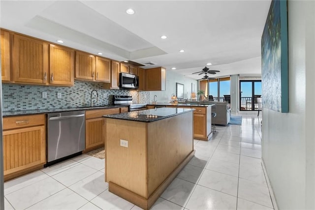 kitchen with sink, a center island, appliances with stainless steel finishes, kitchen peninsula, and backsplash