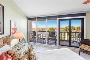 bedroom featuring access to exterior, a wall of windows, tile patterned floors, and vaulted ceiling