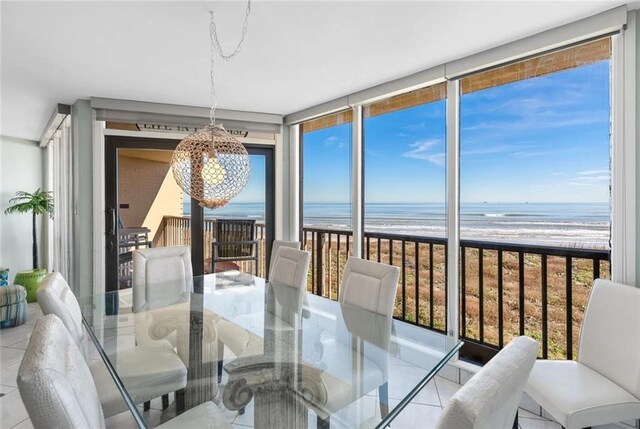 dining space featuring a view of the beach, an inviting chandelier, and a water view