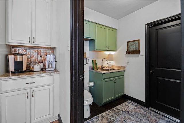 interior space with white cabinets, green cabinets, sink, tasteful backsplash, and light stone counters