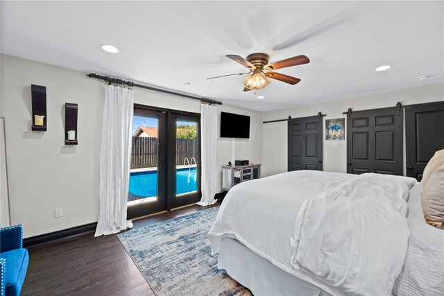 bedroom with access to exterior, a barn door, ceiling fan, and dark wood-type flooring