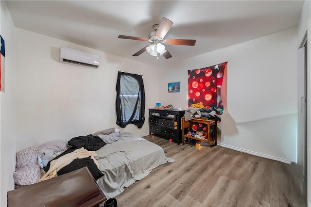 bedroom featuring ceiling fan, a wall mounted air conditioner, and light wood-type flooring