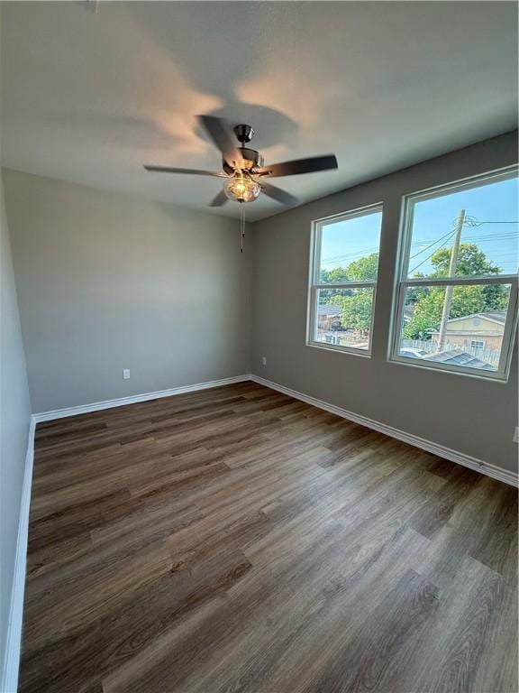 spare room with dark wood-style flooring, baseboards, and a ceiling fan