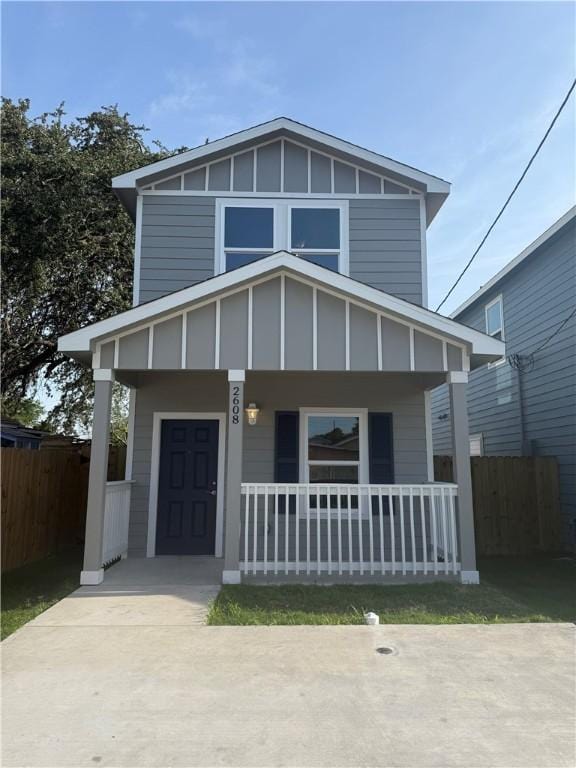 view of front facade with covered porch, board and batten siding, and fence