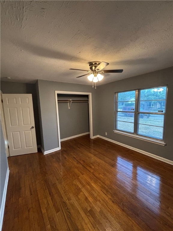 unfurnished bedroom featuring ceiling fan, dark hardwood / wood-style floors, and a textured ceiling