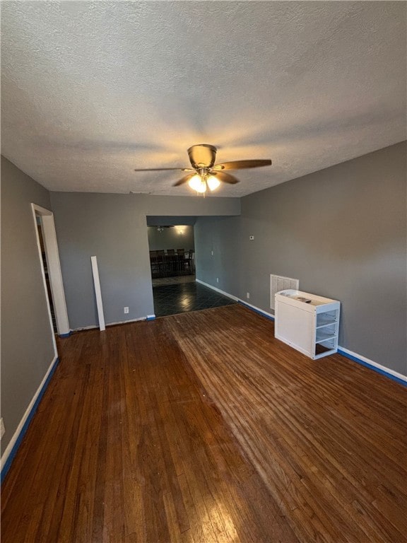 empty room featuring ceiling fan, dark hardwood / wood-style flooring, and a textured ceiling