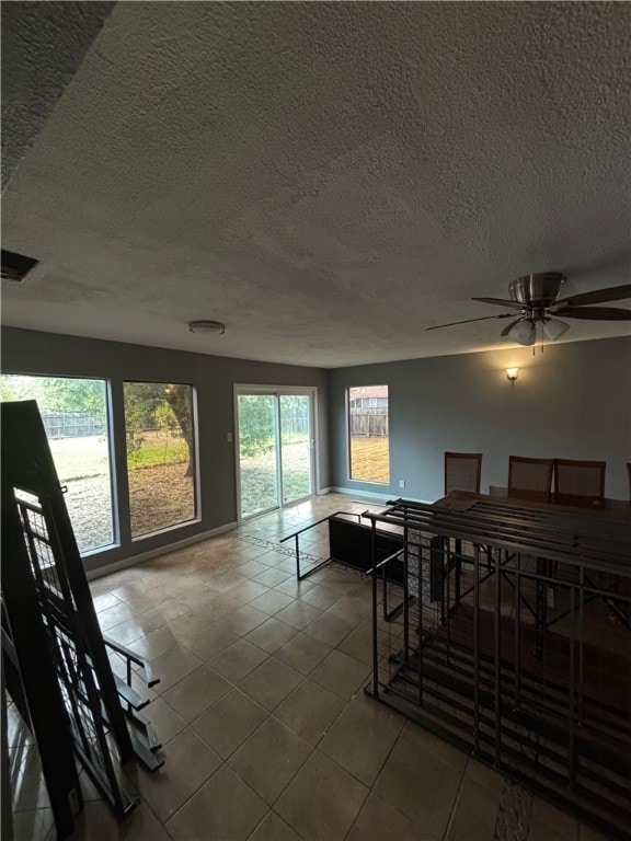 dining area featuring tile patterned flooring, ceiling fan, and a textured ceiling