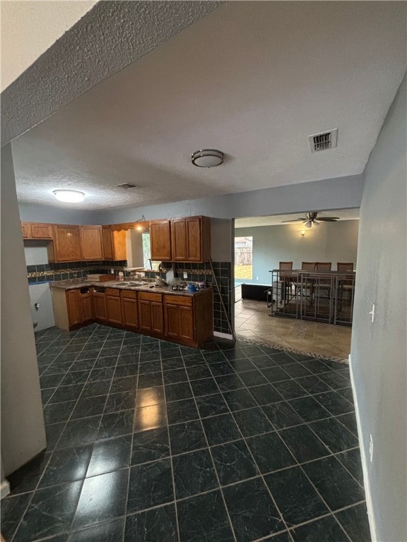 kitchen featuring decorative backsplash, sink, dark tile patterned floors, and ceiling fan