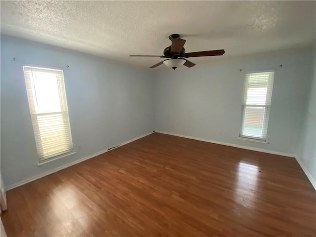 unfurnished room featuring a wealth of natural light and dark hardwood / wood-style floors