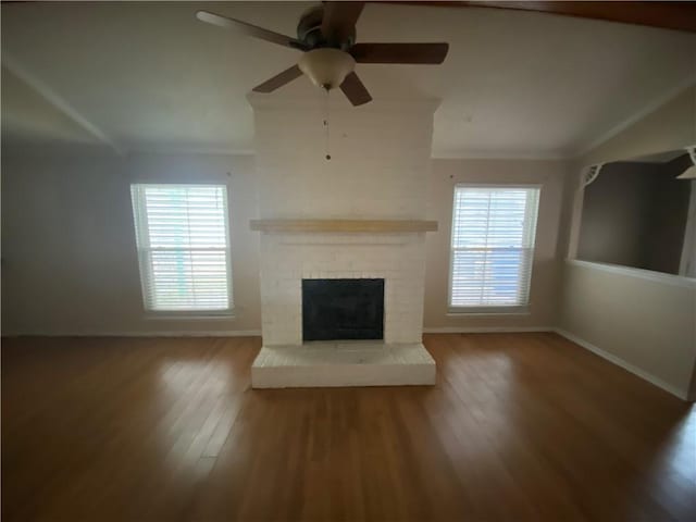 unfurnished living room with ceiling fan, a fireplace, plenty of natural light, and wood-type flooring