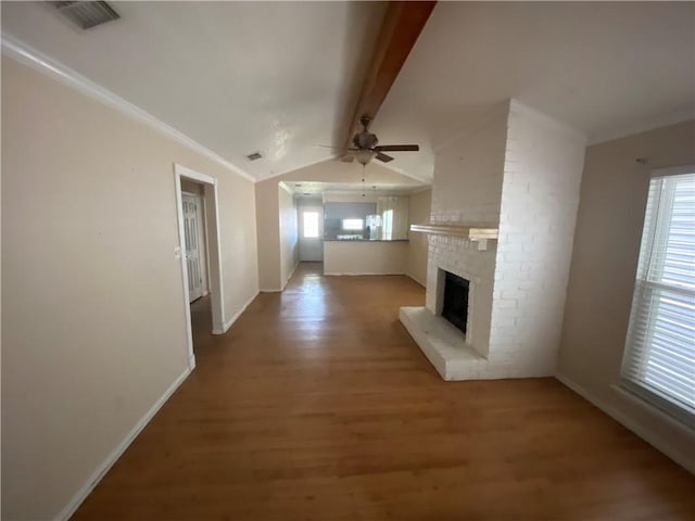 unfurnished living room featuring vaulted ceiling with beams, ceiling fan, ornamental molding, wood-type flooring, and a brick fireplace