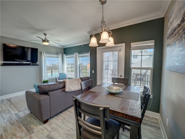 dining room with ornamental molding, light wood-type flooring, a healthy amount of sunlight, and ceiling fan with notable chandelier