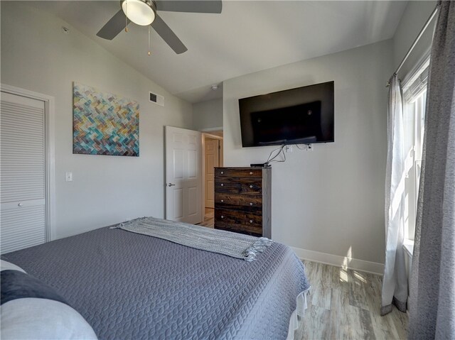 bedroom with hardwood / wood-style floors, ceiling fan, a closet, and vaulted ceiling