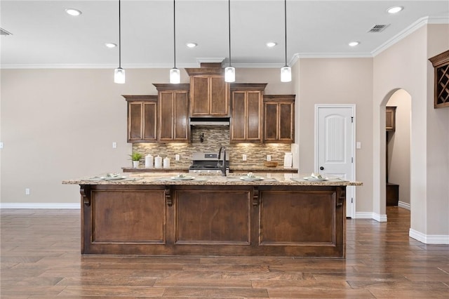 7918 Stampede Dr, Corpus Christi, TX 78414 - kitchen with arched walkways, a sink, tasteful backsplash, baseboards, and under cabinet range hood