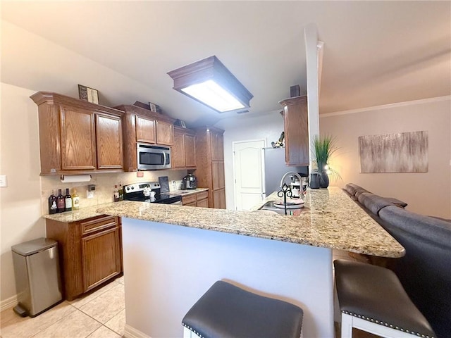 4734 Fox Trot Dr, Corpus Christi, TX 78413 - kitchen with a peninsula, a breakfast bar, light stone counters, light tile patterned floors, and stainless steel appliances