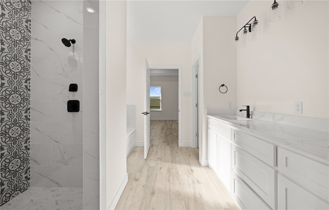 bathroom featuring a tile shower, vanity, and hardwood / wood-style flooring