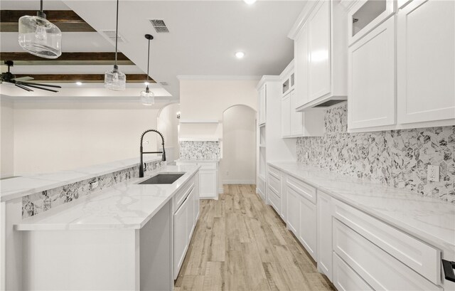 kitchen featuring white cabinets, light wood-type flooring, sink, and hanging light fixtures