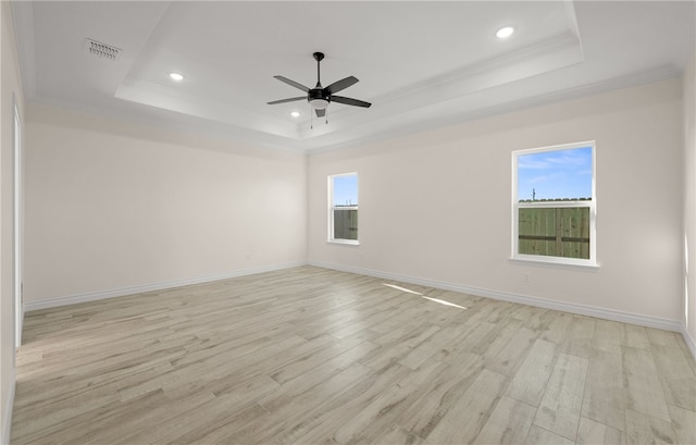 spare room featuring a raised ceiling, light hardwood / wood-style flooring, ceiling fan, and crown molding