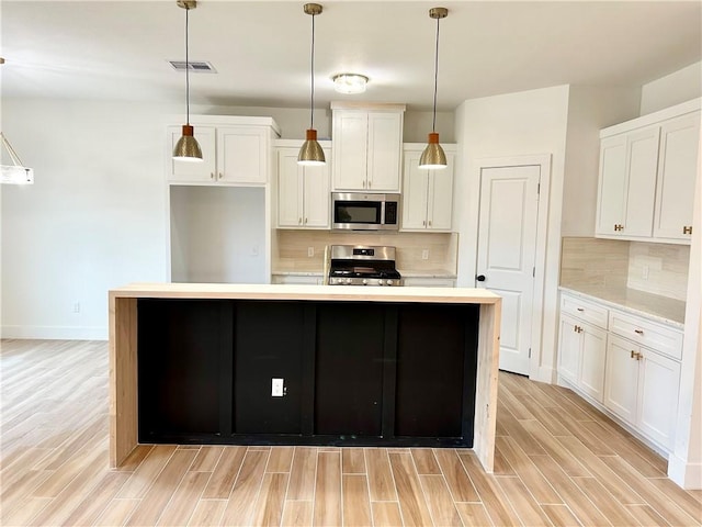 kitchen with stainless steel appliances, wood finish floors, light countertops, and visible vents