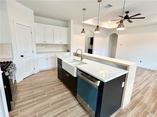 kitchen featuring arched walkways, gas range oven, tasteful backsplash, stainless steel dishwasher, and wood tiled floor