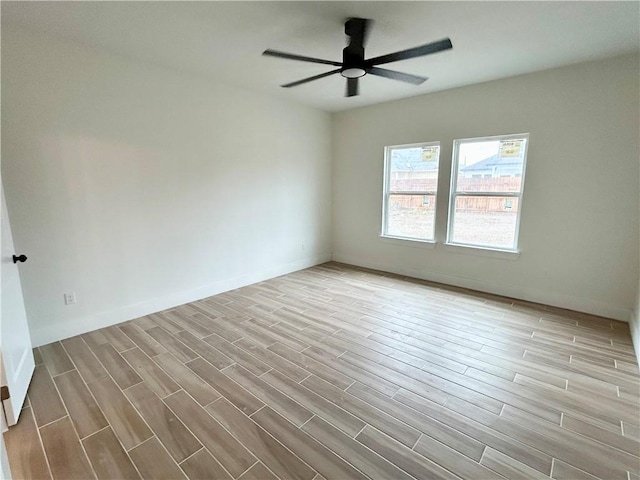 empty room with wood finished floors, a ceiling fan, and baseboards