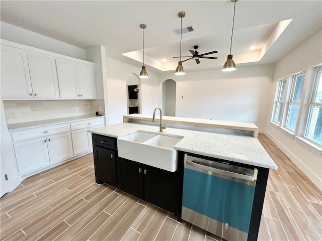 kitchen featuring a tray ceiling, visible vents, a sink, dark cabinetry, and dishwasher