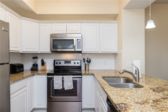 kitchen with white cabinetry, sink, hanging light fixtures, decorative backsplash, and appliances with stainless steel finishes