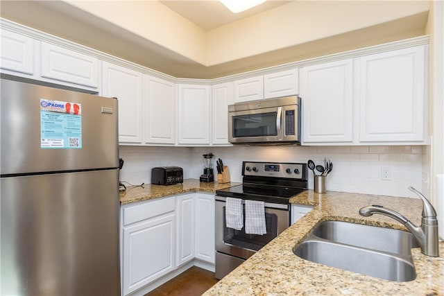 kitchen featuring white cabinets, sink, light stone countertops, tasteful backsplash, and stainless steel appliances