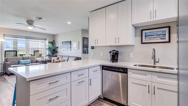 kitchen with a sink, a peninsula, open floor plan, and dishwasher