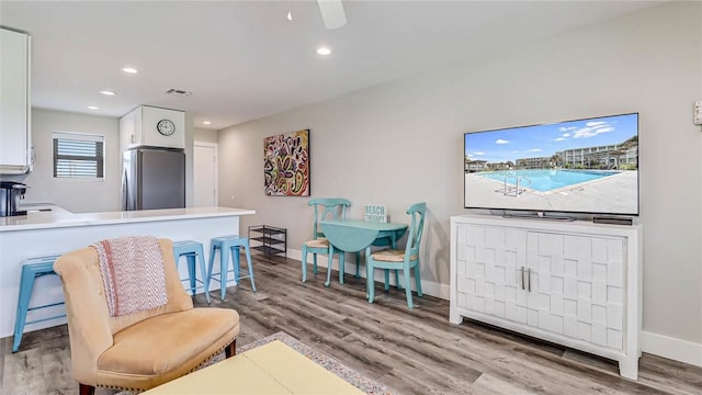 living room featuring recessed lighting, wood finished floors, visible vents, and baseboards