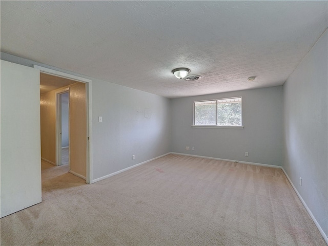 spare room with a textured ceiling and light carpet