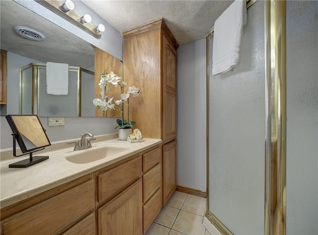 bathroom featuring walk in shower, vanity, a textured ceiling, and tile patterned floors