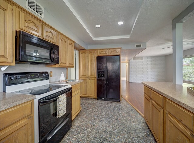 kitchen with black appliances, light brown cabinetry, and a textured ceiling