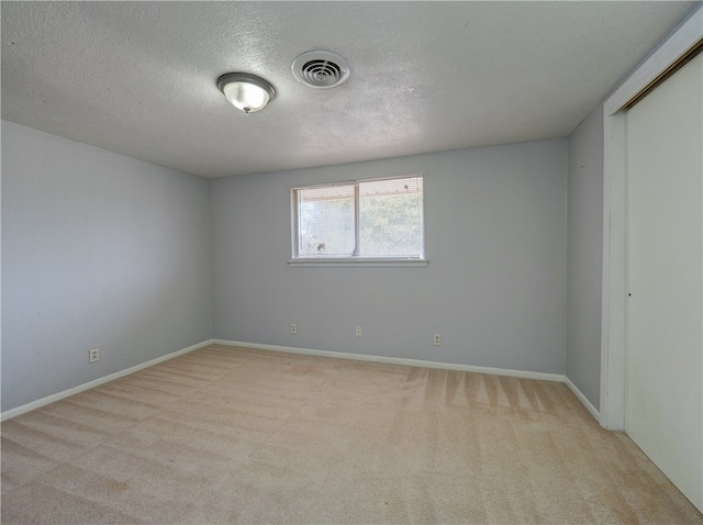 unfurnished room featuring a textured ceiling and light carpet