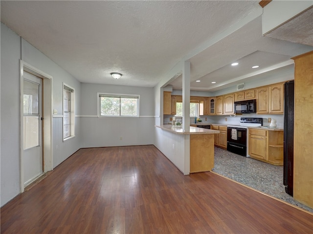 kitchen with dark wood-type flooring, a textured ceiling, black appliances, and kitchen peninsula