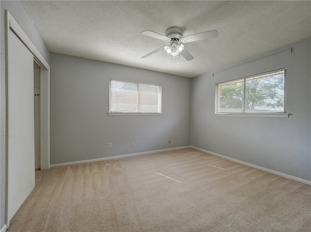 unfurnished bedroom with light carpet, multiple windows, and ceiling fan