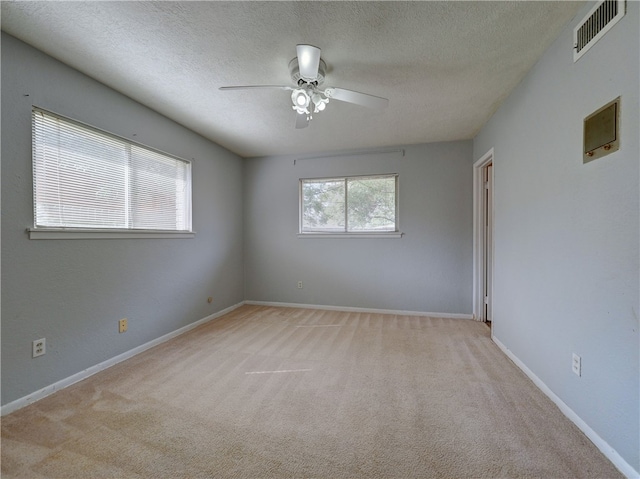 carpeted empty room with ceiling fan and a textured ceiling