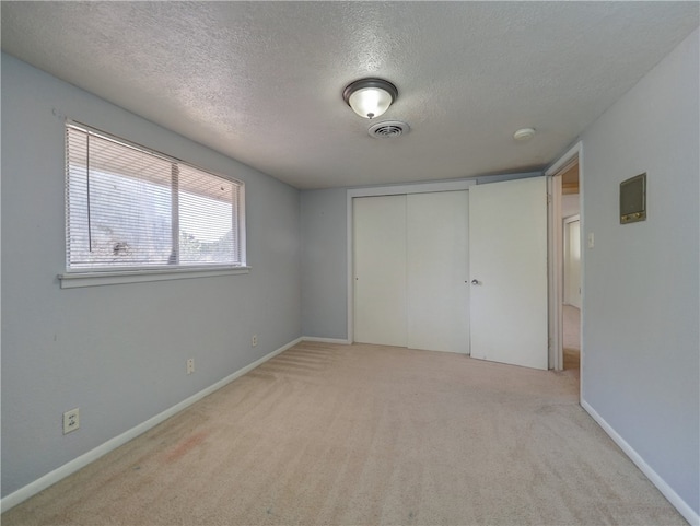 unfurnished bedroom with light colored carpet, a textured ceiling, and a closet