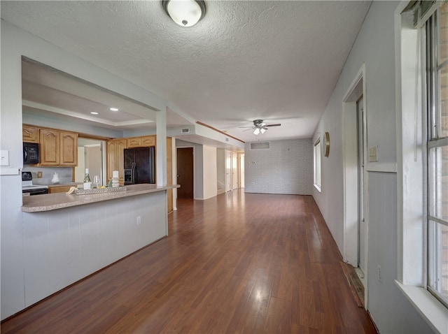 kitchen featuring dark wood-type flooring, kitchen peninsula, black appliances, a textured ceiling, and ceiling fan