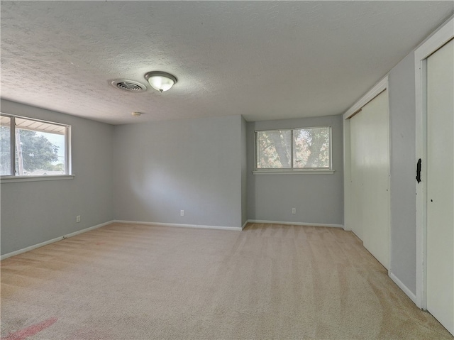 unfurnished bedroom with a textured ceiling and light colored carpet