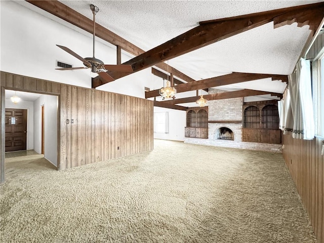 unfurnished living room with beamed ceiling, ceiling fan with notable chandelier, wood walls, and a textured ceiling
