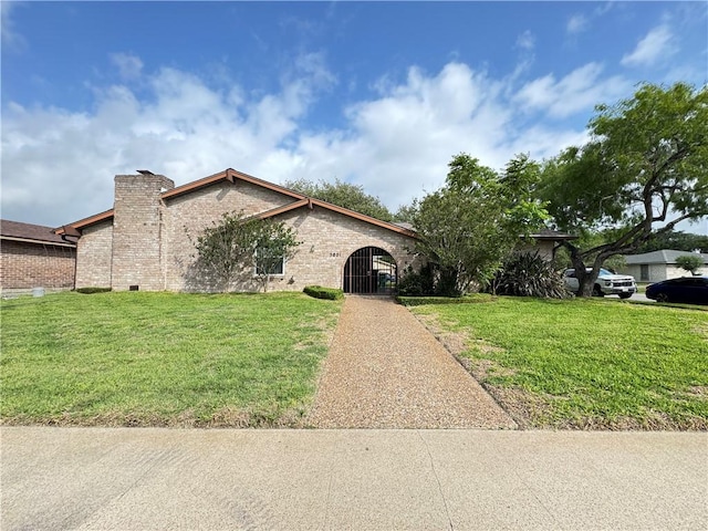 ranch-style house featuring a chimney, brick siding, and a front yard