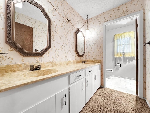full bathroom with double vanity, toilet, a textured ceiling, and a sink