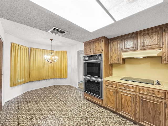 kitchen with a notable chandelier, black electric stovetop, double wall oven, under cabinet range hood, and visible vents