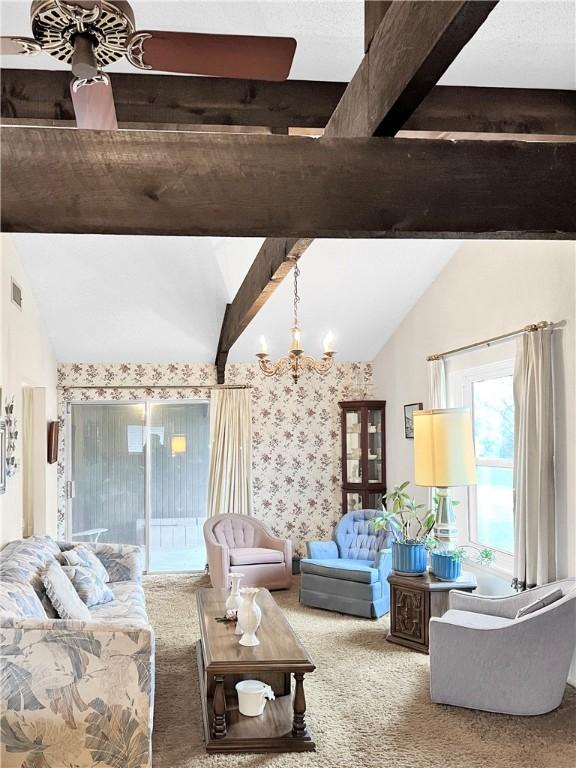 carpeted living room with visible vents, vaulted ceiling with beams, and an inviting chandelier