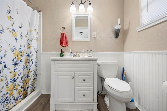 1009 E Sinton St, Sinton, TX 78387 - bathroom with wood finished floors, a wainscoted wall, vanity, toilet, and curtained shower