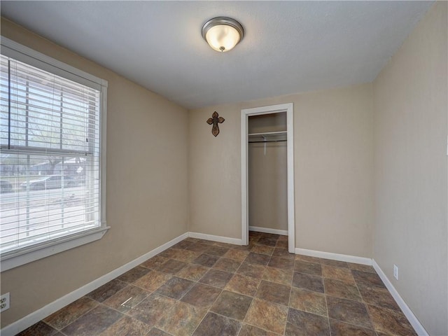 unfurnished bedroom featuring a closet, multiple windows, and baseboards