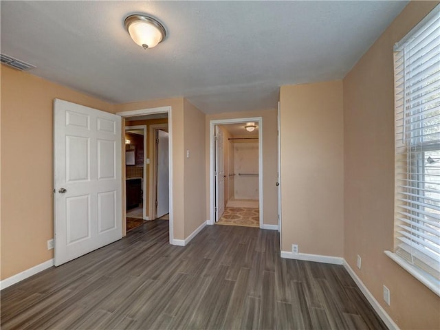 unfurnished bedroom featuring visible vents, baseboards, and dark wood finished floors