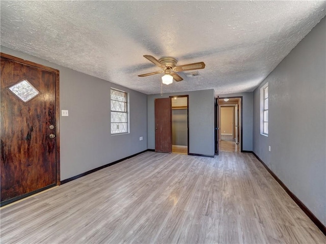 interior space with visible vents, baseboards, light wood-type flooring, and a ceiling fan