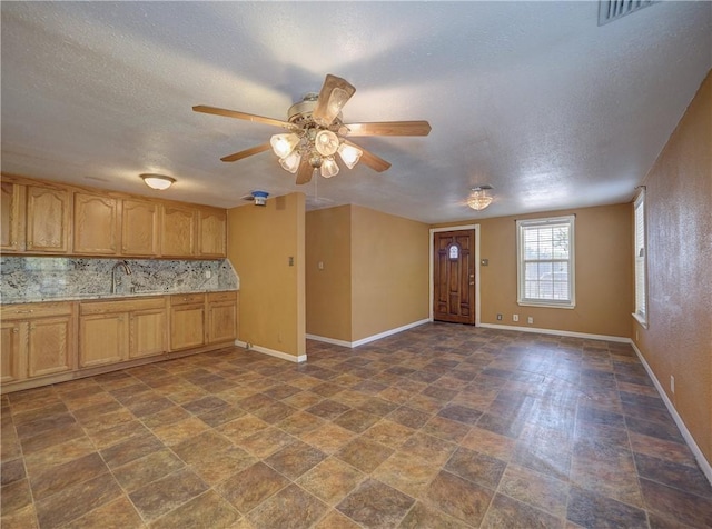 kitchen featuring baseboards, tasteful backsplash, ceiling fan, and light countertops